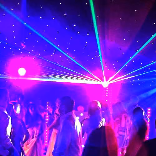 Wedding guests dancing beneath vibrant laser lighting and a starlit dance floor, creating an unforgettable evening reception with a professional wedding DJ