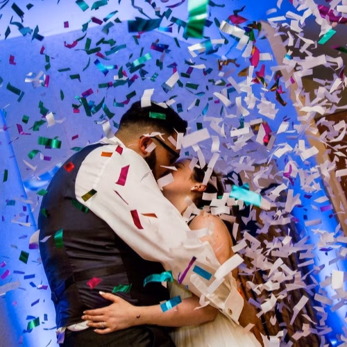 Bride and groom sharing a romantic first dance surrounded by colourful confetti cannons and professional wedding DJ effects in Suffolk, Cambridgeshire and Norfolk.